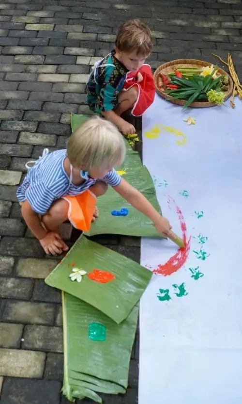 A child painting with natural tools like leaves and sticks, exploring creativity through eco-friendly materials.