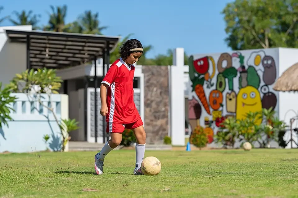 kids in red jersey playing football in field