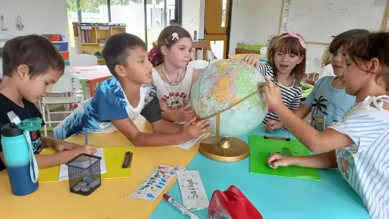 several kids study by seeing a globe in the middle of them