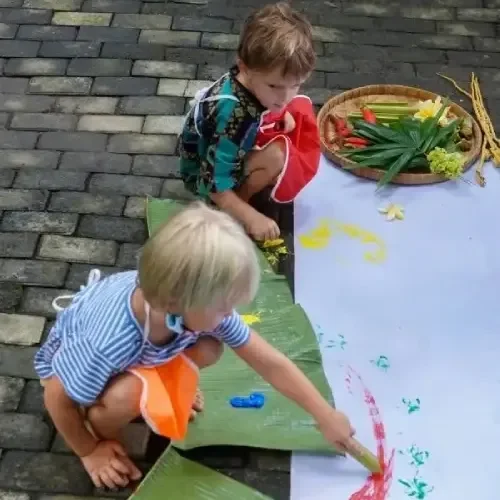 A child painting with natural tools like leaves and sticks, exploring creativity through eco-friendly materials