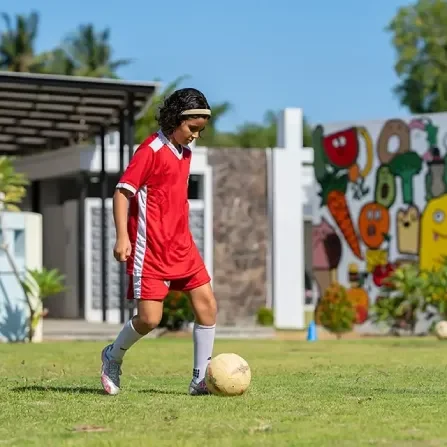 kids in red jersey playing football in field